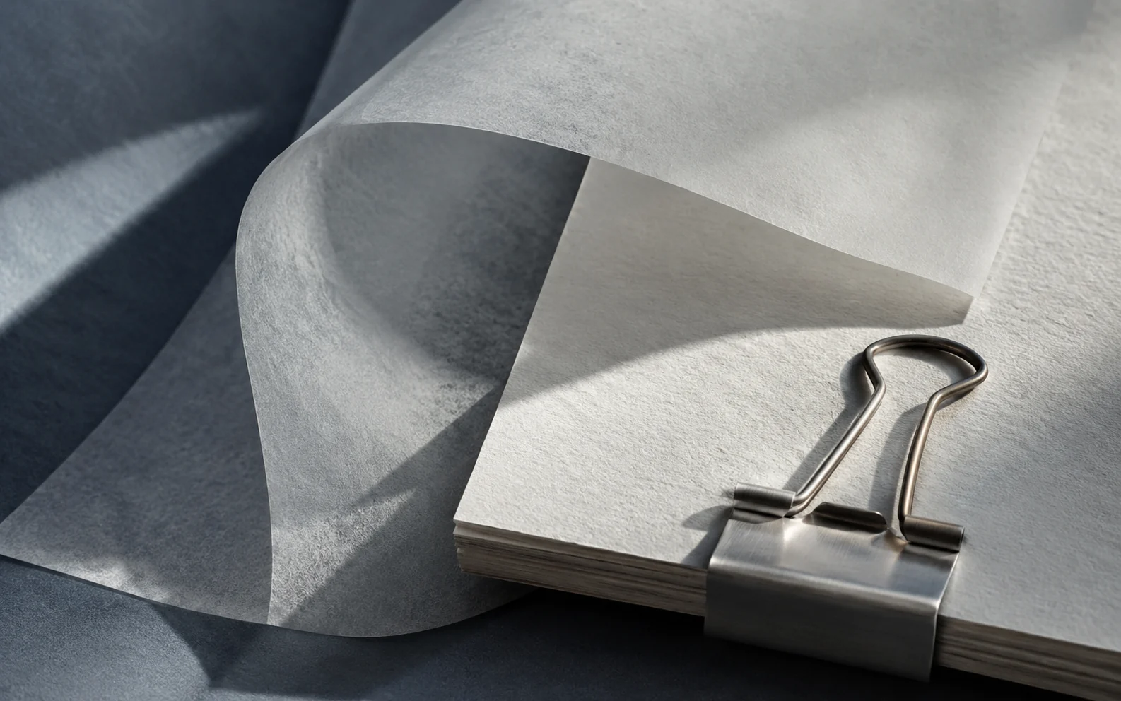 Layers of translucent paper curving over a brushed steel clip